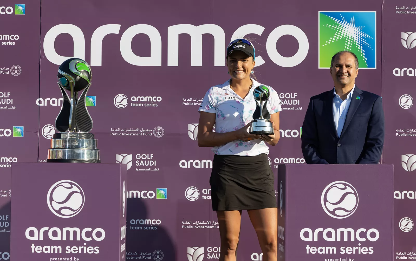 Lexi Thompson raises the individual champion trophy at the recent Aramco Team Series event in New York as Ibrahim Q. Al-Buainain watches on.